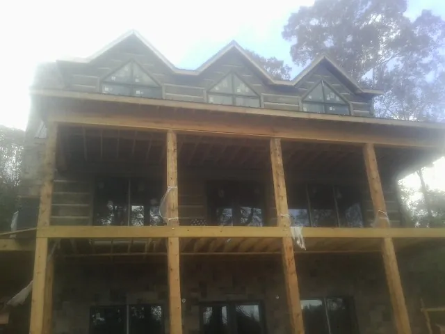 Dormers and porch framing on a large log home under construction — Roof Coating work by our crew in Pawhuska