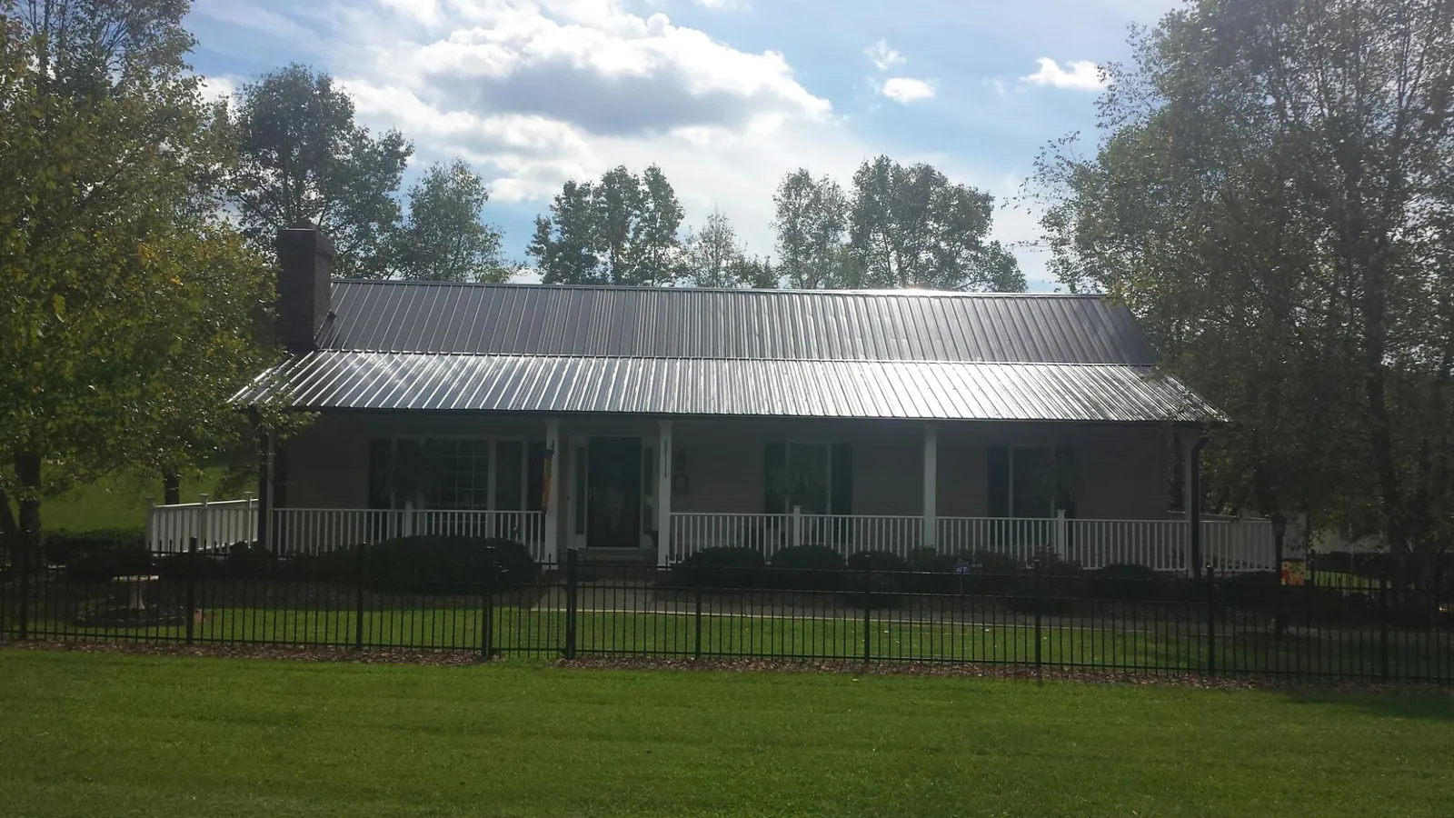 Gray metal roof on a brick ranch with a full width front porch — Gutter Guard Installation work by our crew in Pawhuska