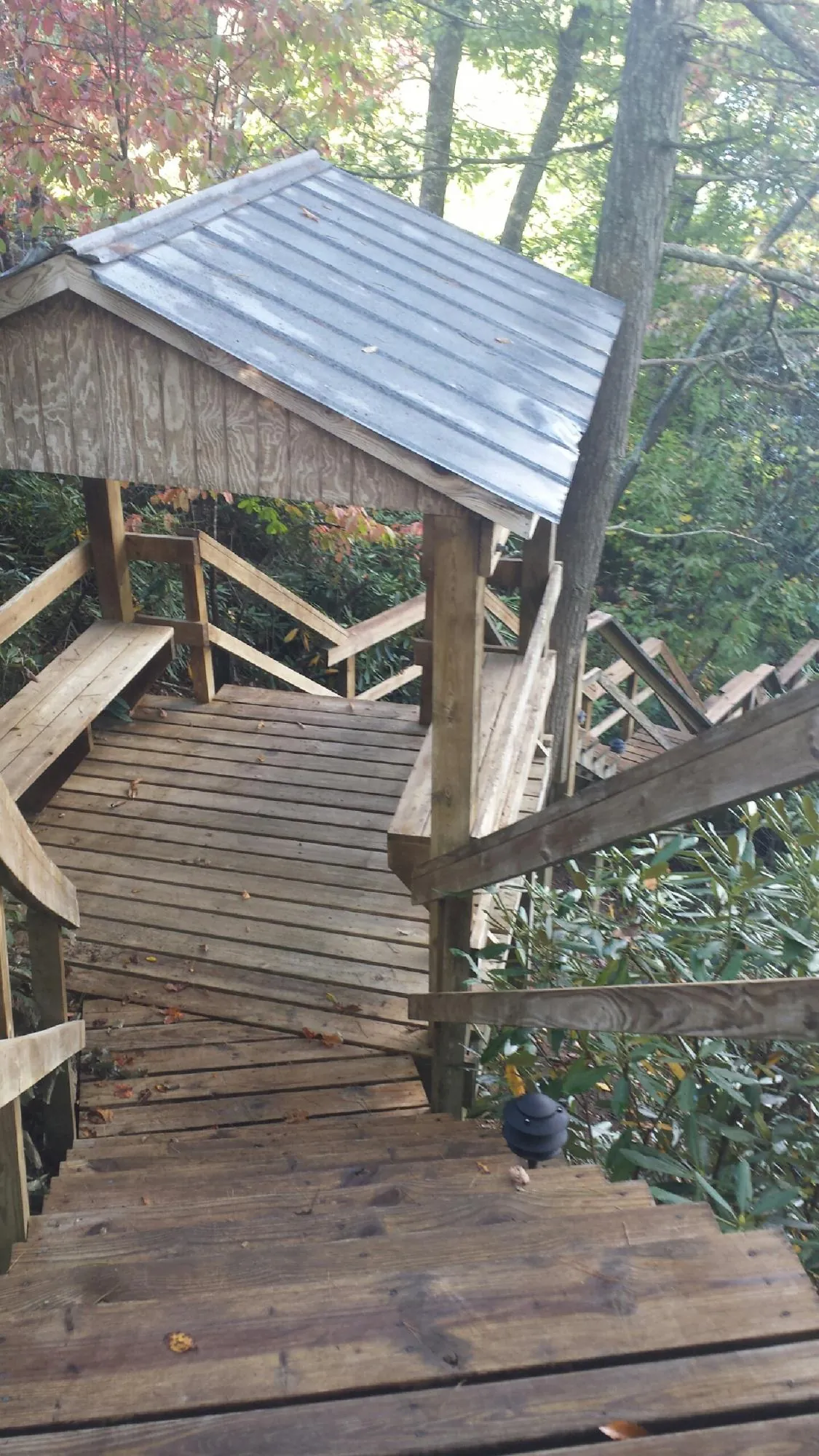 Metal roofed shelter over wooden steps on a wooded walkway — Skylight Repair & Installation work by our crew in Pawhuska