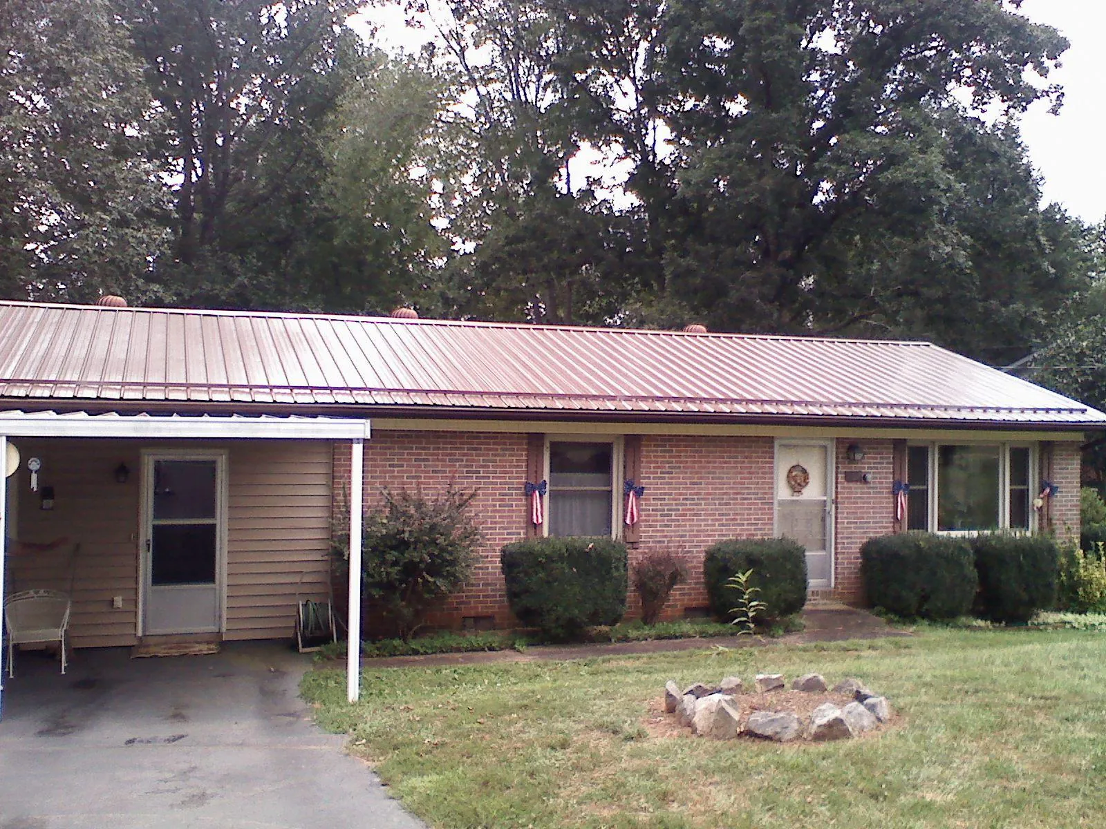 Bronze metal roof and carport on a brick ranch home — Roof Repair work by our crew in Pawhuska