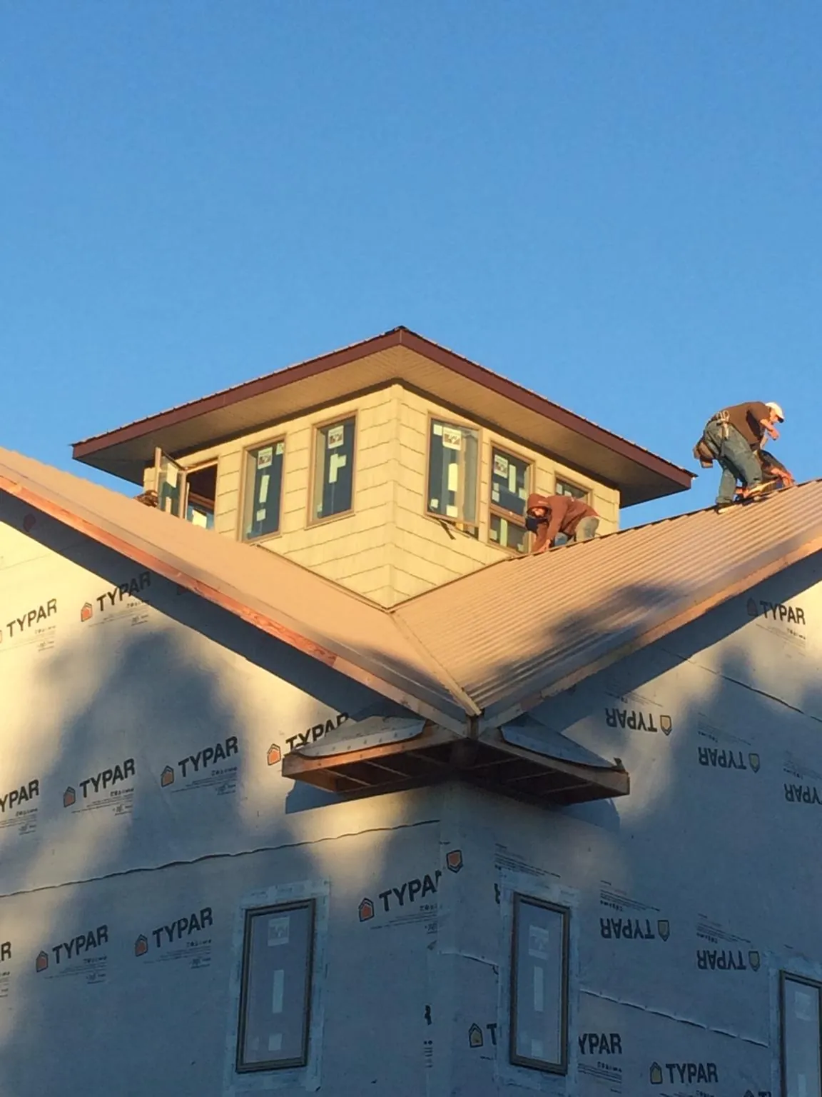 Roofers working around a rooftop cupola on a new metal roof at sunset — Roof Waterproofing in Pawhuska by Roofing Brothers